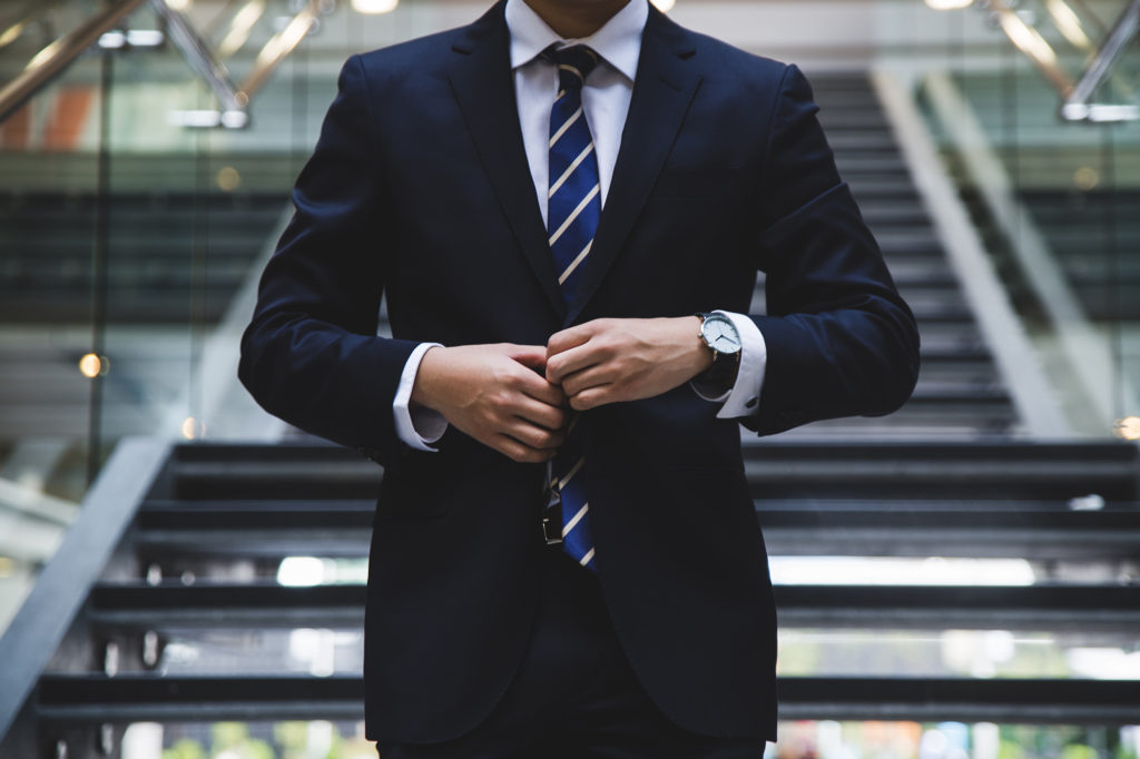 Man in a suit with watch at the foot of a staircase